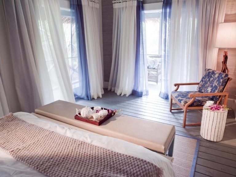 Habitación de lujo con banco tapizado y terraza en Tiamo Resort, decorada con cortinas azules y blancas