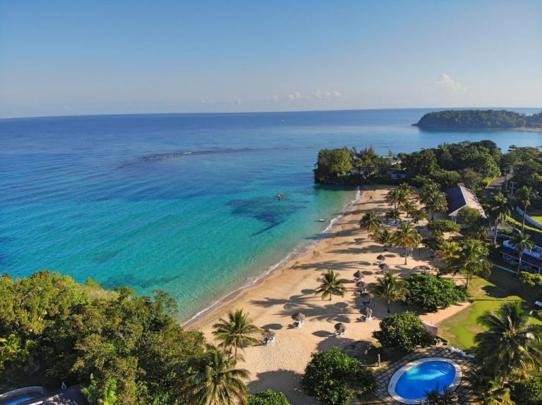 Vista aérea de la playa y piscina del Jamaica Inn con aguas turquesas del Caribe y palmeras