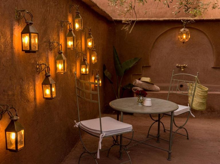 Patio exterior romántico con faroles artesanales y mesa de hierro forjado en Casa Abracadabra Marruecos