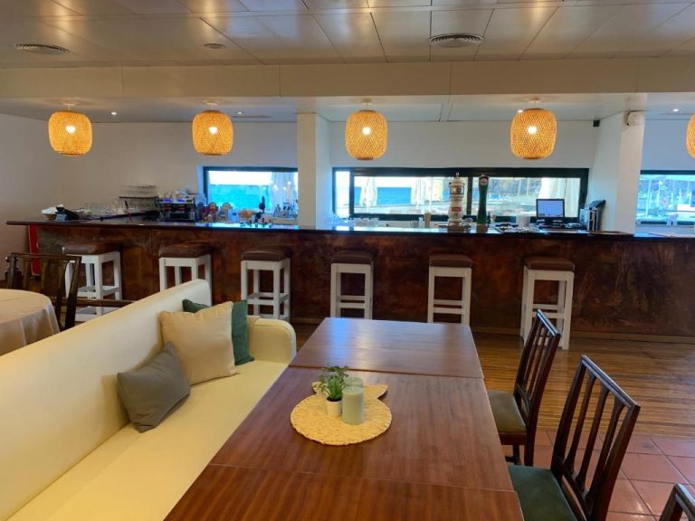 Bar y zona de restaurante con barra de madera y sofás blancos en Quinta da Penha de Franca
