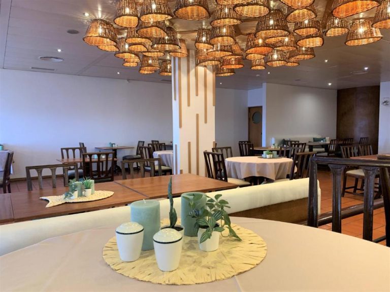 Restaurante interior del Quinta da Penha de Franca con lámparas de mimbre y mesas elegantemente decoradas