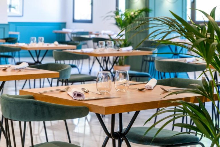 Restaurante del hotel ARTIEM Audax Adults Only con mesas de madera, sillas verdes y plantas decorativas