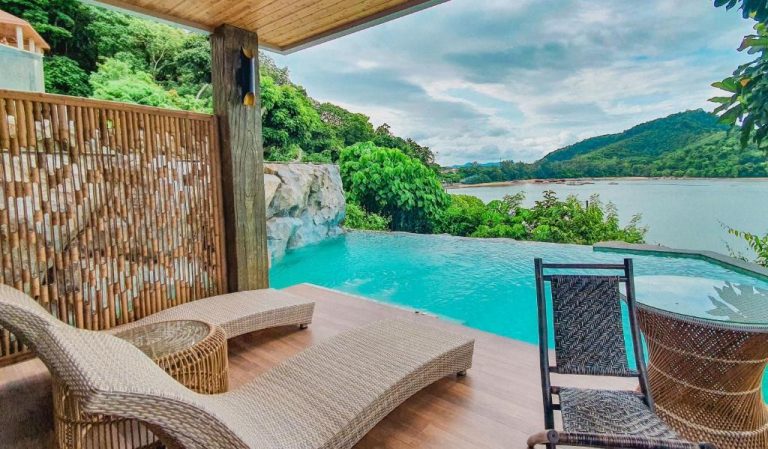 Piscina infinita con terraza y vistas al mar rodeada de naturaleza en SINAE Phuket Luxury Hotel