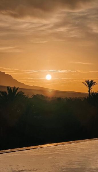 Espectacular puesta de sol sobre el desierto con palmeras y montañas en Kasbah Hnini