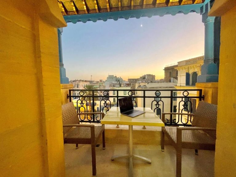 Terraza con mesa y laptop del Royal Victoria Ex British Embassy con vistas panorámicas a la ciudad al atardecer