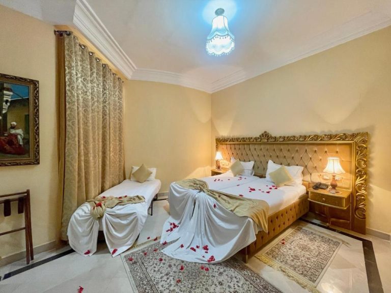 Habitación doble de lujo con pétalos de rosas y cabecero dorado en Royal Victoria Ex British Embassy