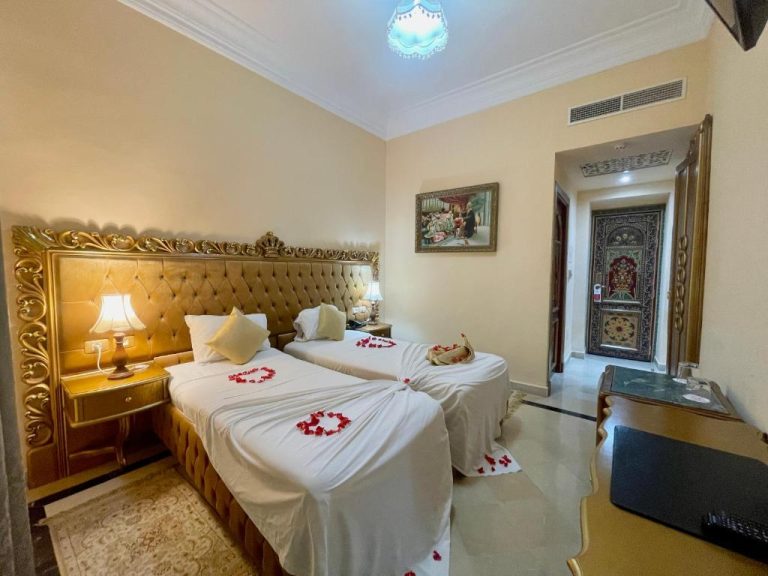 Habitación doble romántica con pétalos de rosa y cabecero dorado en Hotel Royal Victoria Ex British Embassy