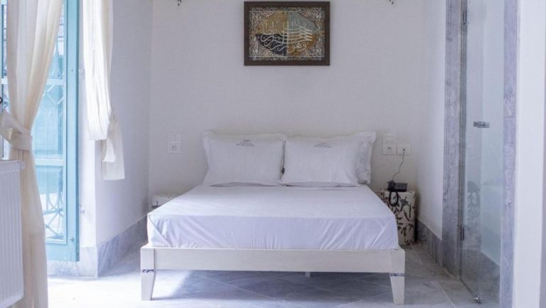 Habitación doble de estilo minimalista con cama blanca y decoración árabe en Dar Ben Gacem Kahia
