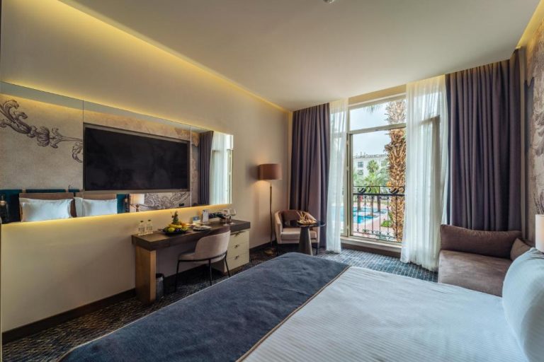 Habitación superior con vistas a la piscina exterior en IC Hotels Airport, con escritorio y TV de pantalla plana