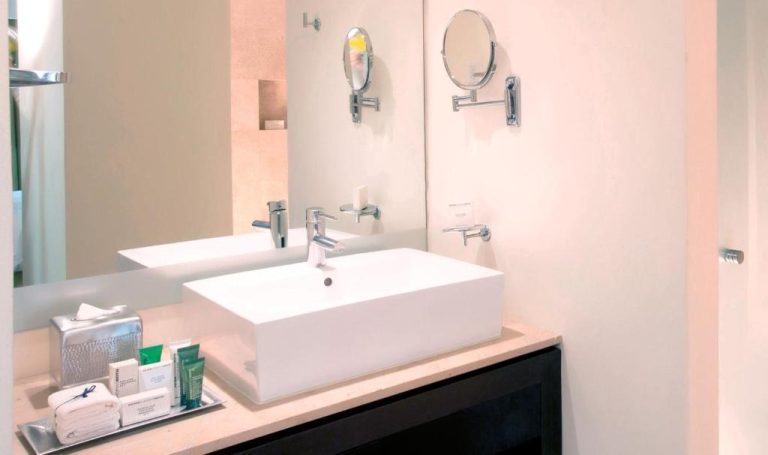 Baño moderno con lavabo blanco empotrado y espejos de pared en Krystal Grand Puerto Vallarta All Inclusive