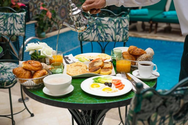 Desayuno completo con huevos, cruasanes y té en terraza junto a la piscina del Hotel Safia