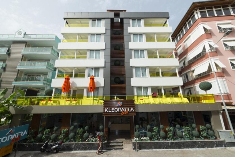 Fachada exterior del Kleopatra Suit Hotel con terraza y sombrillas naranjas en Alanya