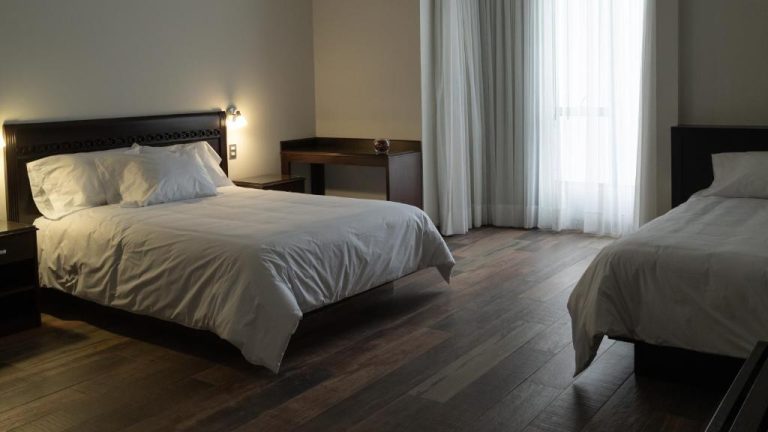 Habitación doble con dos camas y suelo de madera oscura en el hotel Lima Host