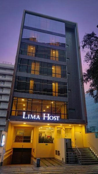 Fachada exterior iluminada del hotel Lima Host en Lima, edificio moderno de varios pisos con entrada principal