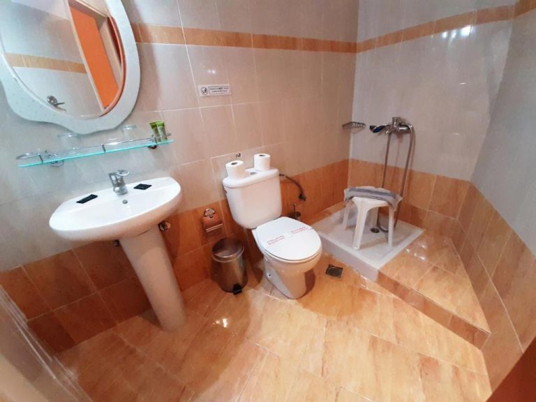 Baño completo con ducha, lavabo y aseo del Mitho Hotel Spa con azulejos en tonos beige