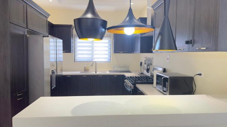 Cocina moderna con gabinetes oscuros y lámparas colgantes negras en Jamnick Vacation Rentals, Jamaica