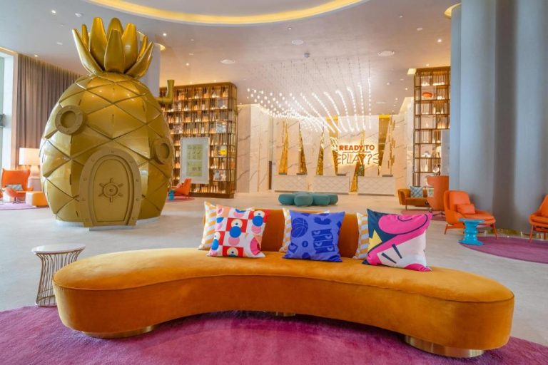 Lobby del Nickelodeon Hotels Riviera Maya con réplica dorada de la piña de Bob Esponja y sofá curvo naranja