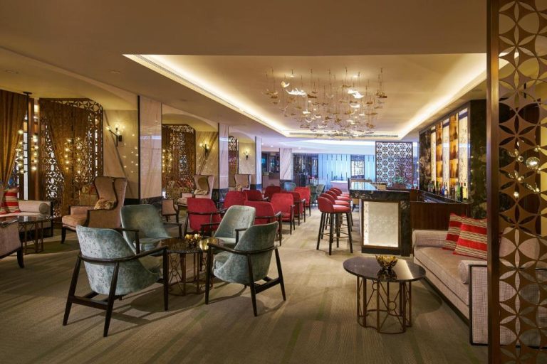 Elegante bar lounge del Orchard Rendezvous Hotel con sillones de terciopelo y barra iluminada