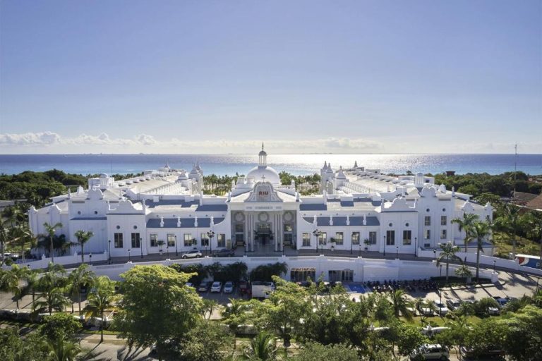 Vista aérea de la imponente fachada blanca del Riu Palace Riviera Maya con vistas al mar Caribe