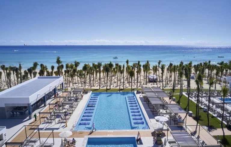 Piscina exterior con tumbonas y palmeras frente a la playa del Riu Palace Riviera Maya All Inclusive