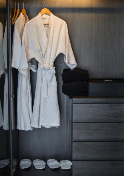 Albornoces blancos y zapatillas de cortesía en el armario del hotel Glam Habitat SHA Extra Plus