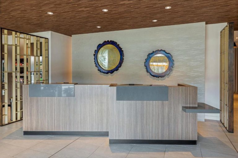Recepción moderna con mostrador de madera y espejos decorativos en Fairfield by Marriott Alajuela