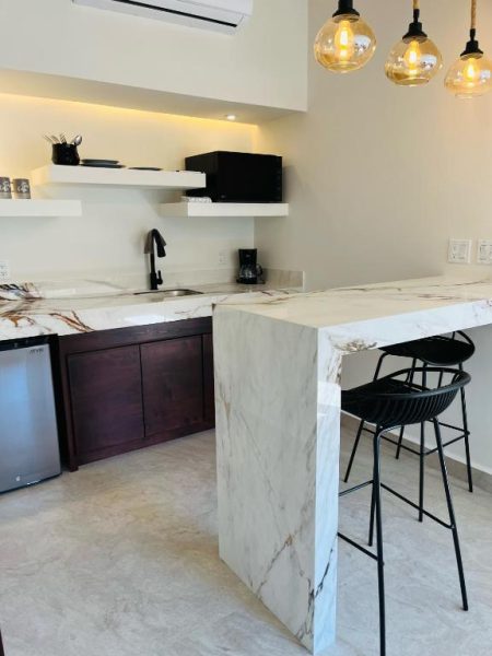 Cocina moderna con encimera de mármol blanco y barra de desayuno en Marisol Hotel Boutique