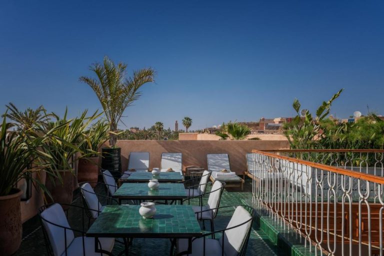 Terraza exterior con mesas de mosaico verde y vistas a la medina del Riad Le Saadien en Marrakech