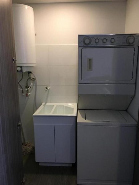 Zona de lavandería con lavadora y secadora apilada en apartamento del Enjoy In Bogotá