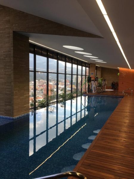 Piscina interior climatizada con vista panorámica a la ciudad en el hotel Enjoy In Bogotá