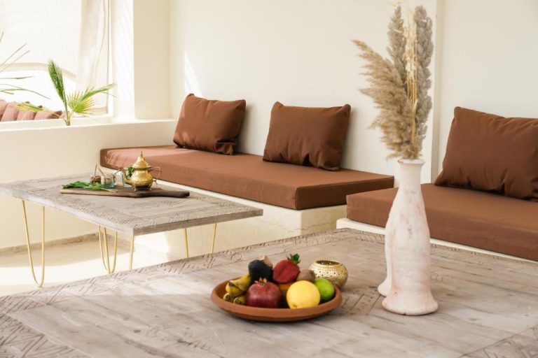 Salón de estilo marroquí con sofás en tierra y mesa de madera en Riad Rahal