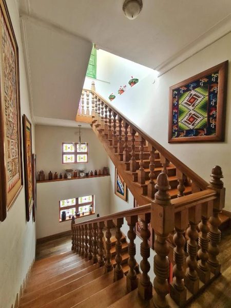 Escalera de madera artesanal con barandilla torneada y arte tradicional en Hotel Antigua Miraflores