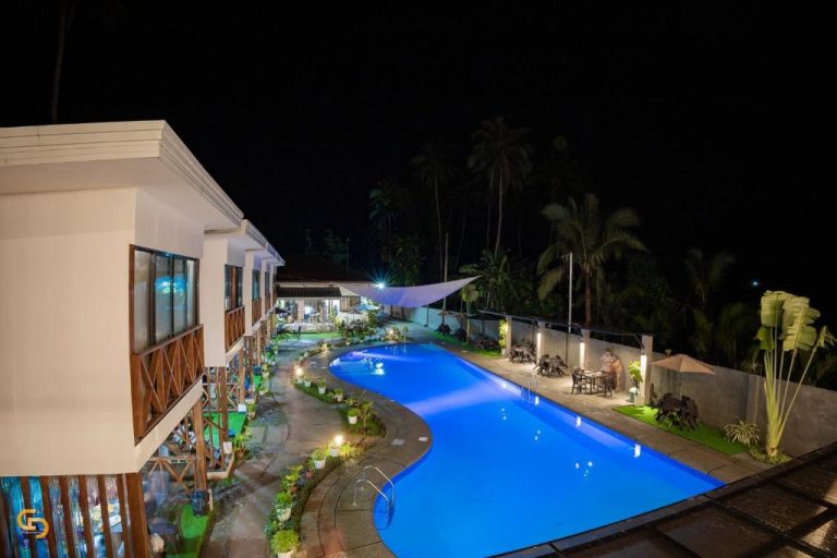 Piscina iluminada de noche en Bakawan Hideaway Resort and Restaurant rodeada de palmeras tropicales