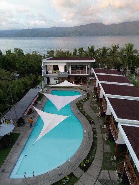 Piscina exterior con velas de sombra del Bakawan Hideaway Resort frente al lago y montañas