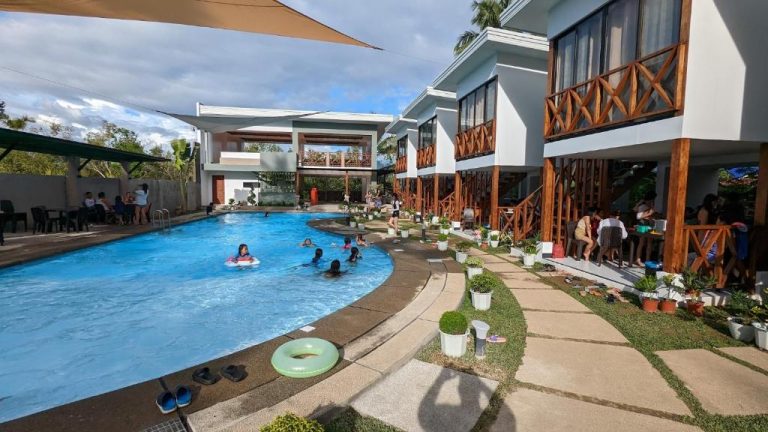 Piscina exterior con bañistas y villas con terraza de madera en Bakawan Hideaway Resort and Restaurant
