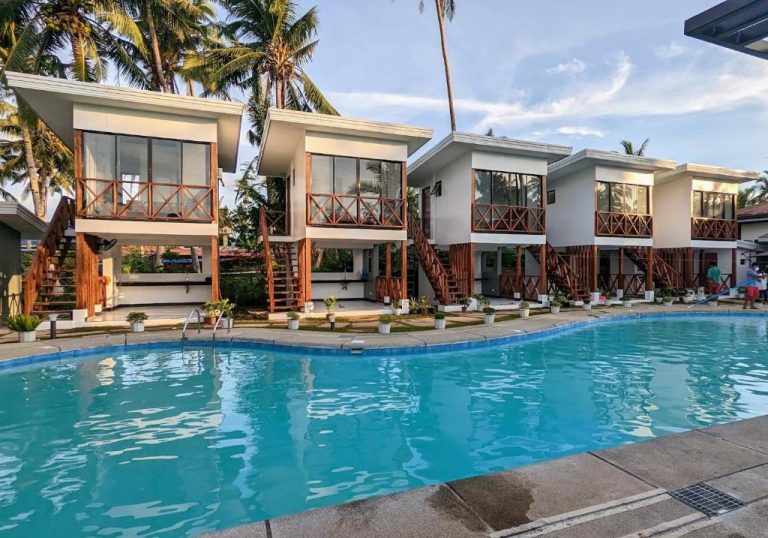 Piscina exterior con bungalows de dos plantas y palmeras en Bakawan Hideaway Resort and Restaurant