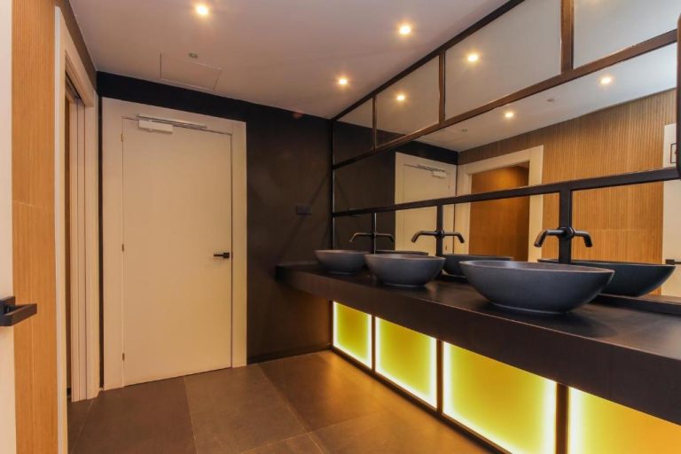 Baño moderno con lavabos negros y iluminación LED amarilla en el Hotel Lauria