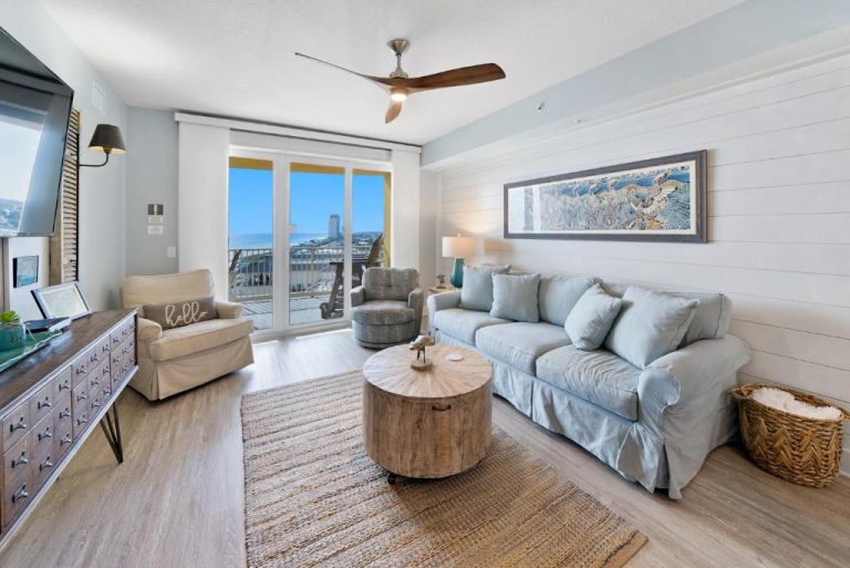 Sala de estar con sofá azul, mesa de madera y balcón con vistas al mar en Calypso 3 Luxury Beach