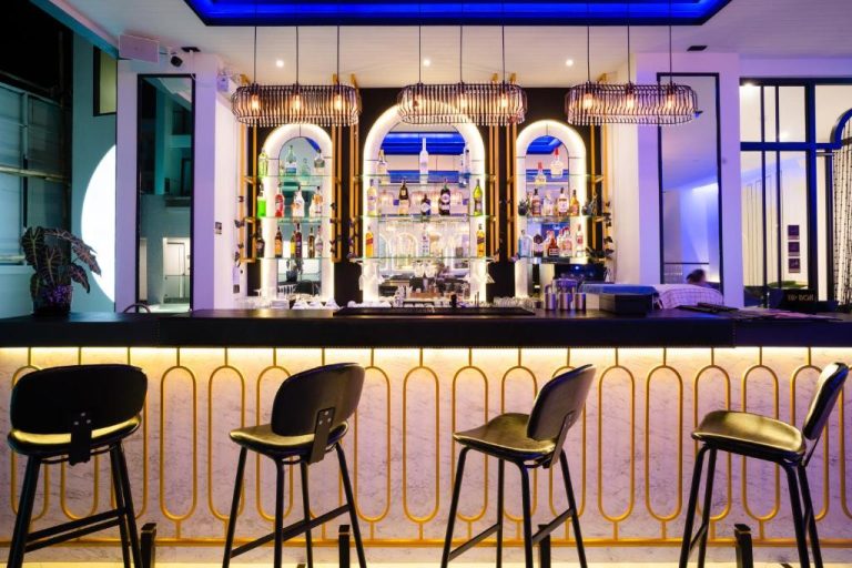 Bar de cócteles elegante con iluminación azul y dorada en Ratri Hotel Phuket Old Town