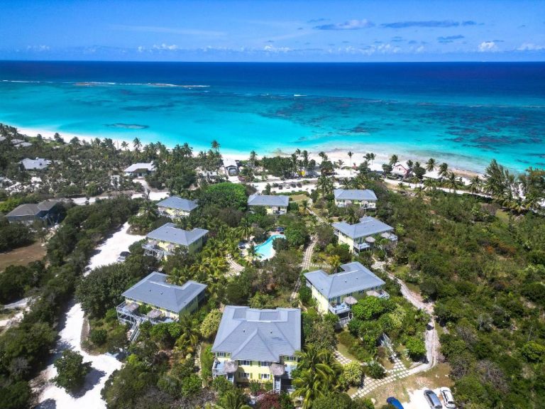Vista aérea del resort Pineapple Fields con villas, piscina y playa de aguas turquesas en Bahamas