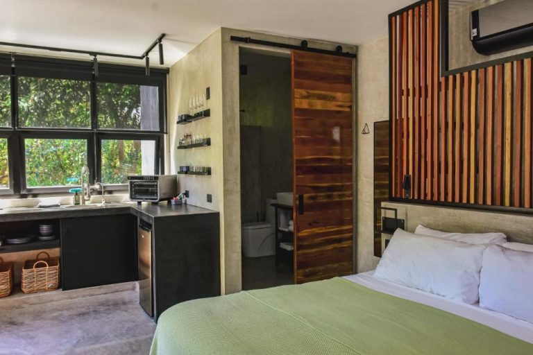 Habitación estudio con cocina integrada, cama doble y puerta corredera de madera en LOTE4 LGBTQ Studios