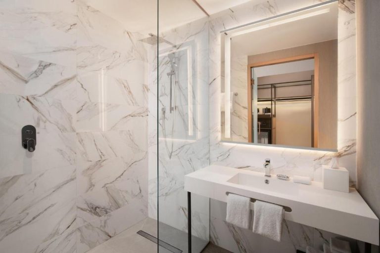 Baño de mármol blanco con ducha independiente y lavabo moderno en AC Hotel by Marriott Punta Cana