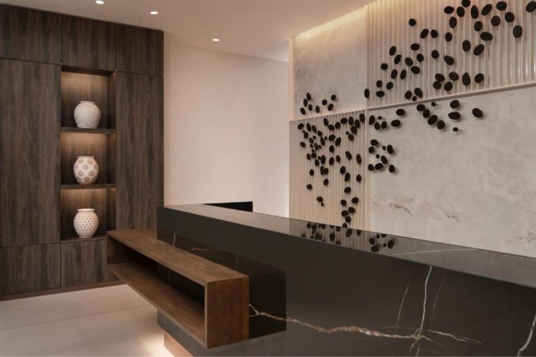 Recepción de diseño moderno con mostrador de mármol negro y arte decorativo en AC Hotel Marriott Punta Cana