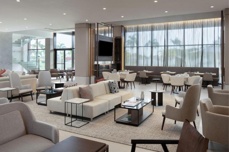 Elegante lobby lounge con sofás blancos y vistas a palmeras en AC Hotel by Marriott Punta Cana