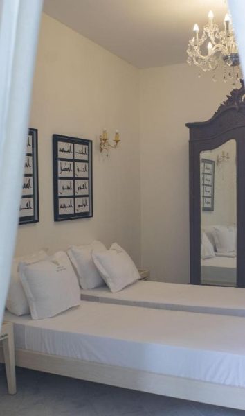 Habitación doble elegante con lámpara de araña y espejo antiguo en Dar Ben Gacem Kahia