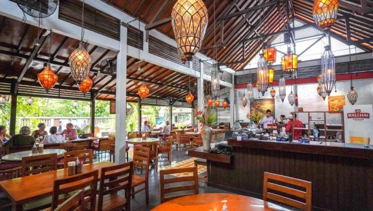 Restaurante interior con lámparas tradicionales balinesas y terraza abierta del Bali Garden Beach Resort