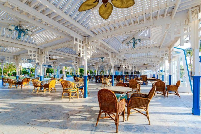 Terraza restaurante exterior con sillas de mimbre y pérgola blanca en The Grand Hotel Hurghada