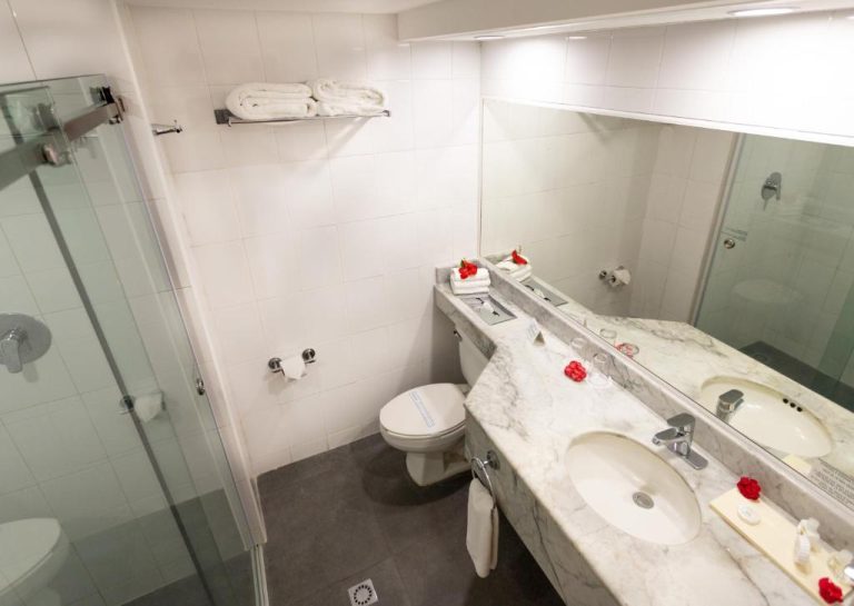 Baño moderno con encimera de mármol, ducha acristalada y doble lavabo en Posada Real Los Cabos