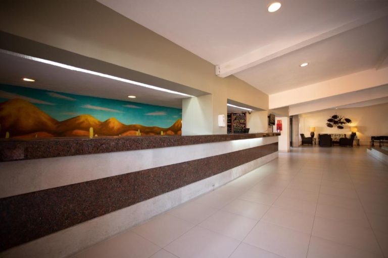 Recepción y lobby del hotel Posada Real Los Cabos con mostrador de granito y mural decorativo