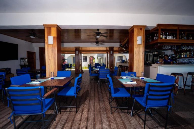 Restaurante y bar interior con sillas azules y techo de madera en Blue Skies Beach Resort